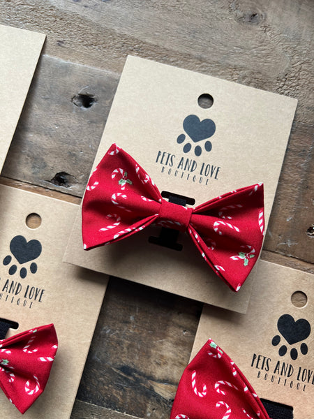 Red Candy Cane patterned pet bowties displayed on kraft paper tags printed with the brand name 'Pets and Love Boutique', arranged on a rustic wooden surface.
