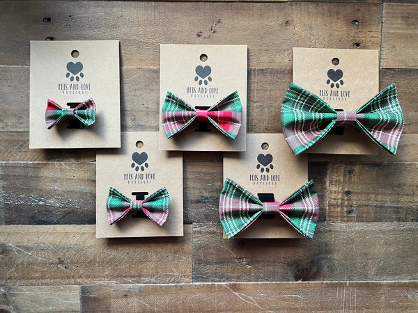 Five different size pet bow ties in plaid patterns of green, white, and red, each mounted on a kraft paper card.