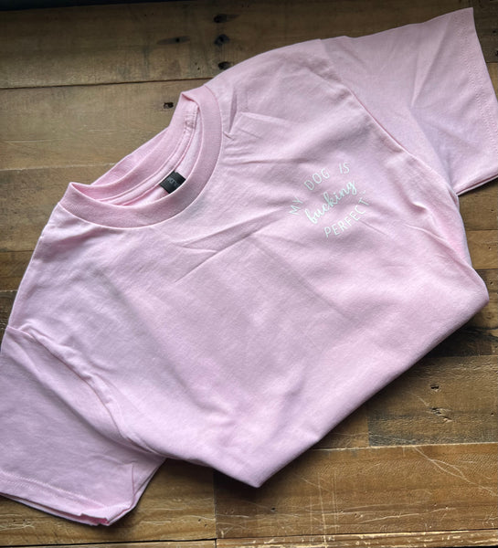 Pink t-shirt with My Dog Is Fucking Perfect on a wooden surface