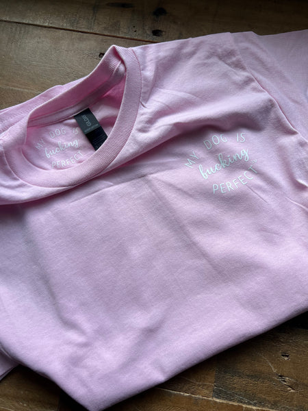 Pink t-shirt with My Dog Is Fucking Perfect on a wooden surface